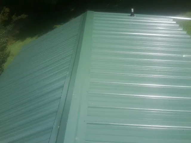 New green metal panels meeting at the ridge of a roof — Flat Roof Repair work by our crew in Grand Lake