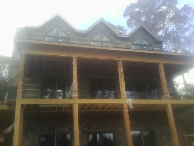 Dormers and porch framing on a large log home under construction — Roof Coating work by our crew in Grand Lake