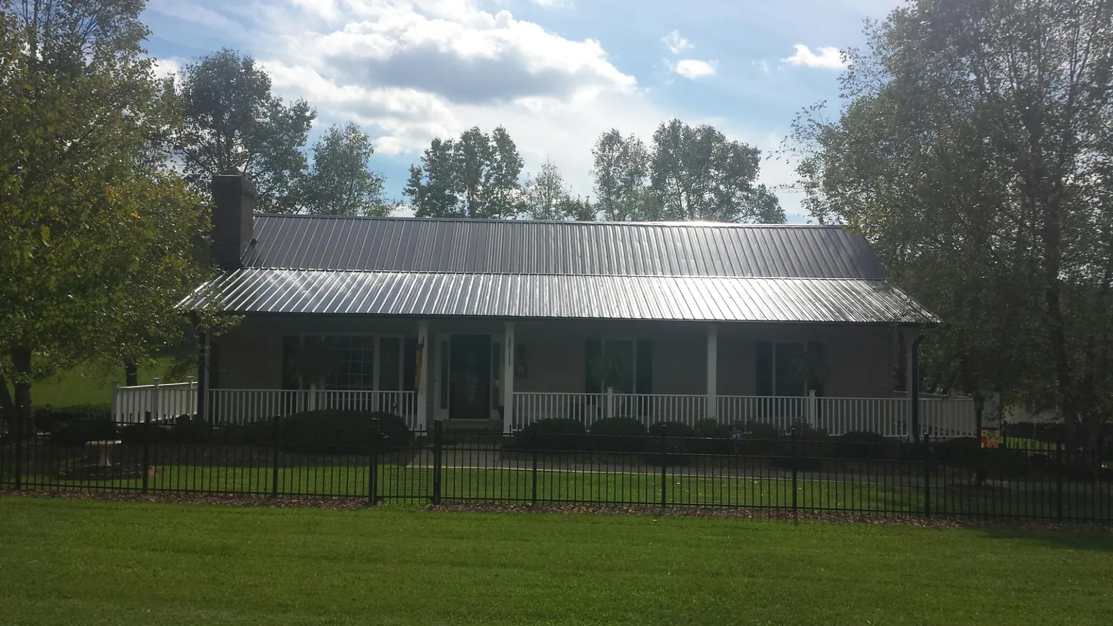 Gray metal roof on a brick ranch with a full width front porch — Gutter Guard Installation work by our crew in Grand Lake