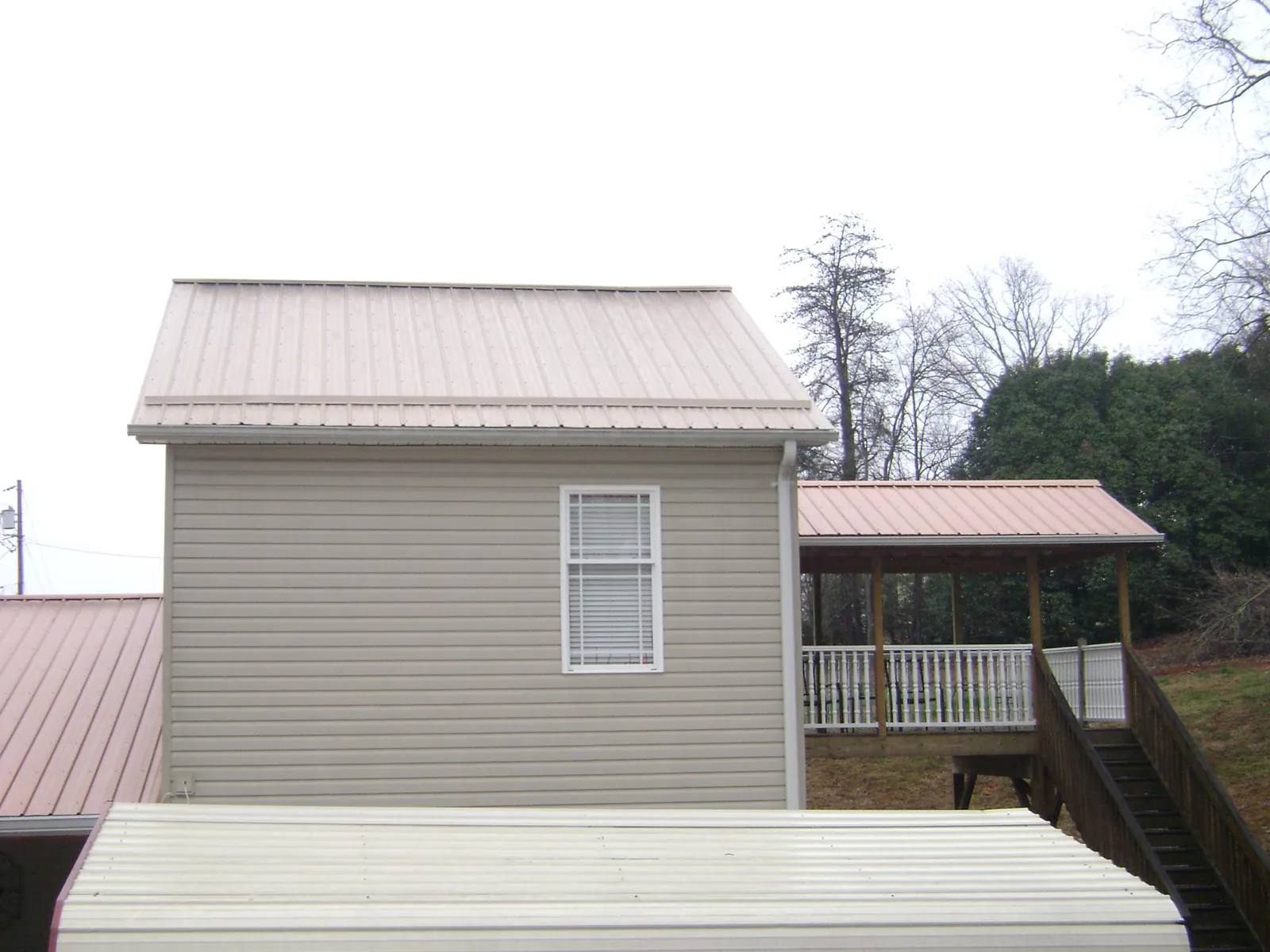 Tan metal roofs on a two story addition and attached porch, from a Roof Replacement job in Grand Lake