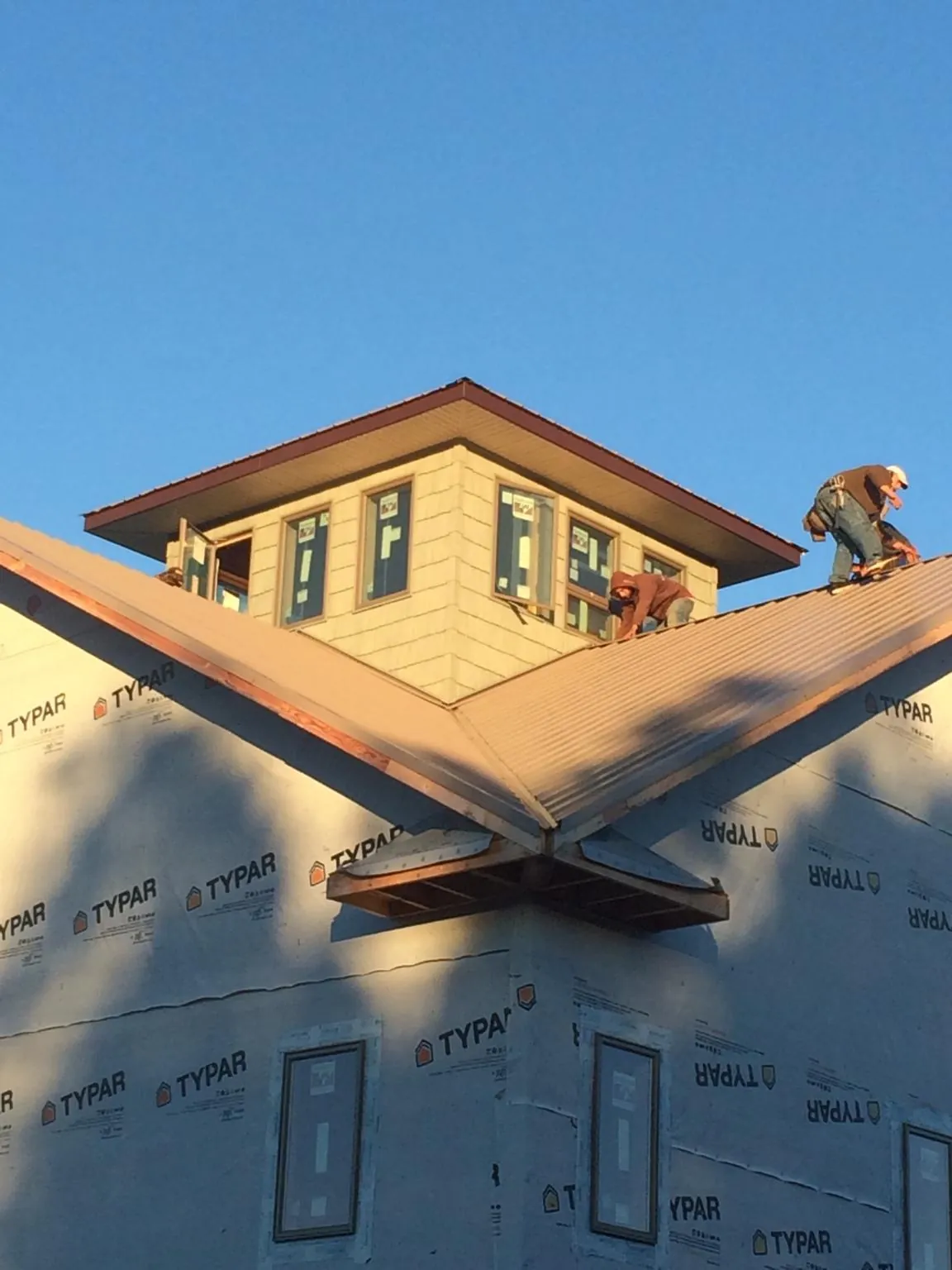 Roofers working around a rooftop cupola on a new metal roof at sunset — Roof Waterproofing in Grand Lake by Roofing Brothers